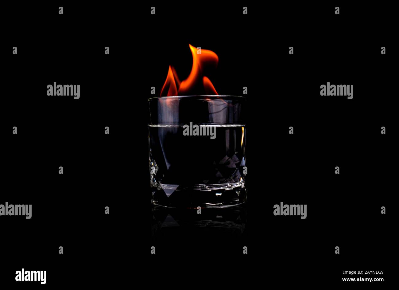 Vetro con vodka e fuoco fiamma su sfondo nero Foto Stock