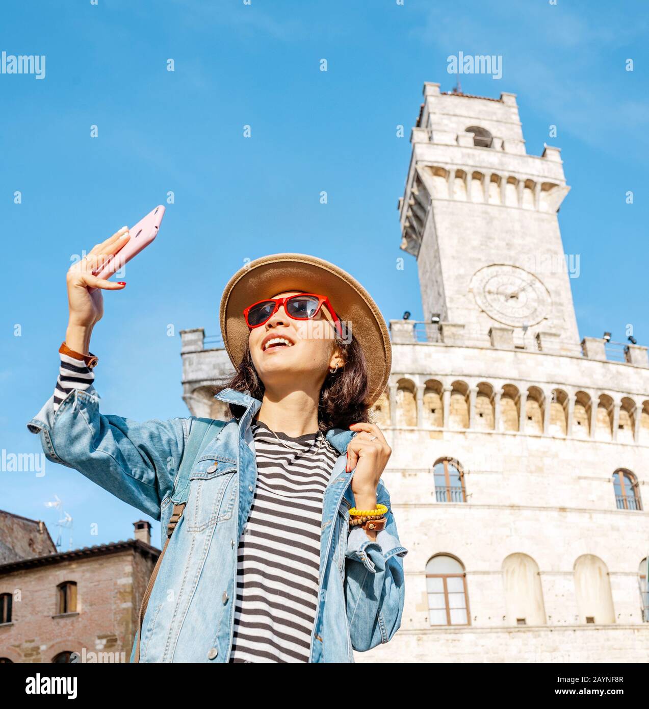 Felice donna turistica asiatica con smartphone nel centro storico di Montepulciano, Toscana. Vacanze e viaggi in Italia concetto Foto Stock