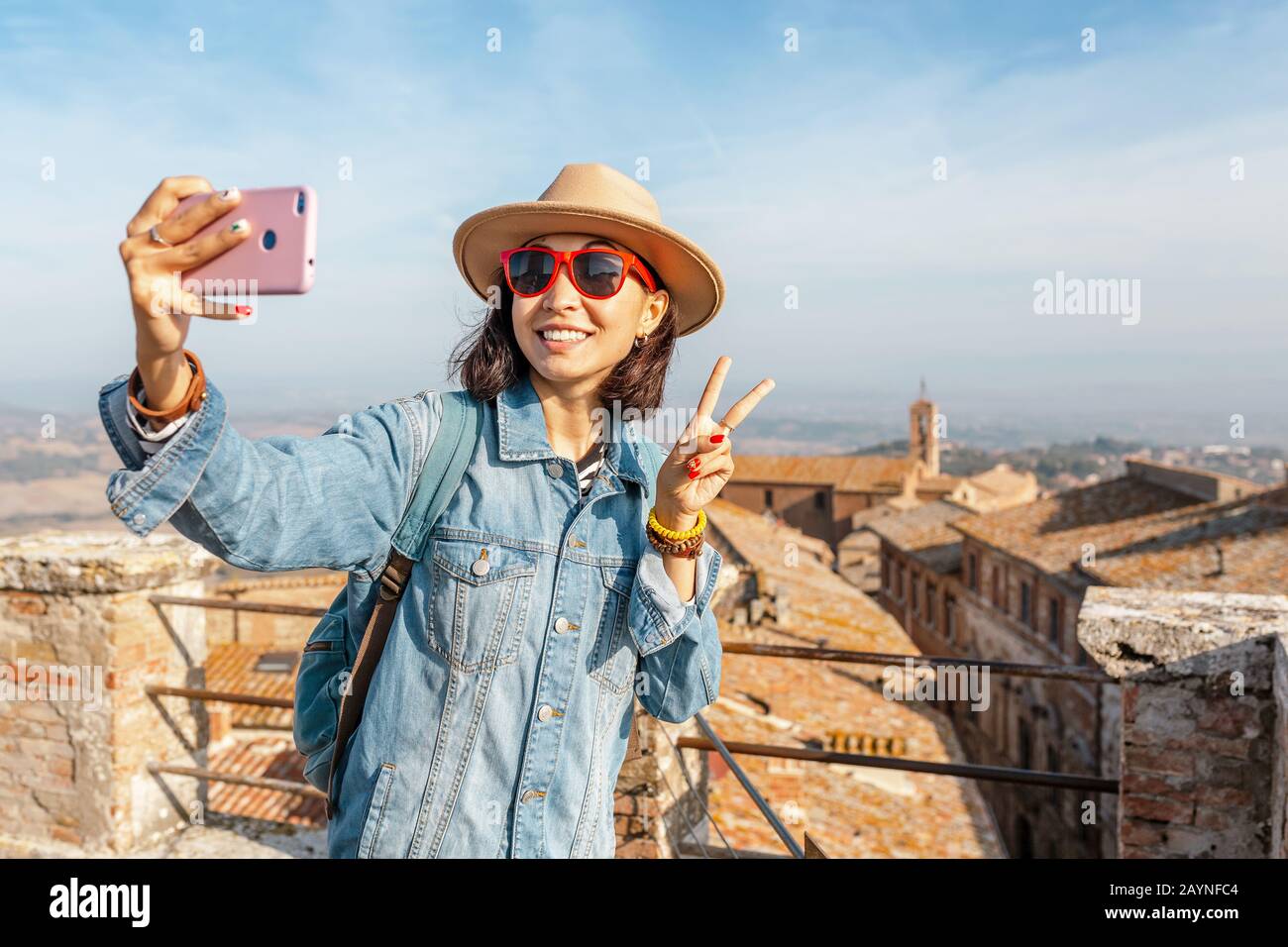 Felice donna turistica asiatica con smartphone nel centro storico di Montepulciano, Toscana. Vacanze e viaggi in Italia concetto Foto Stock