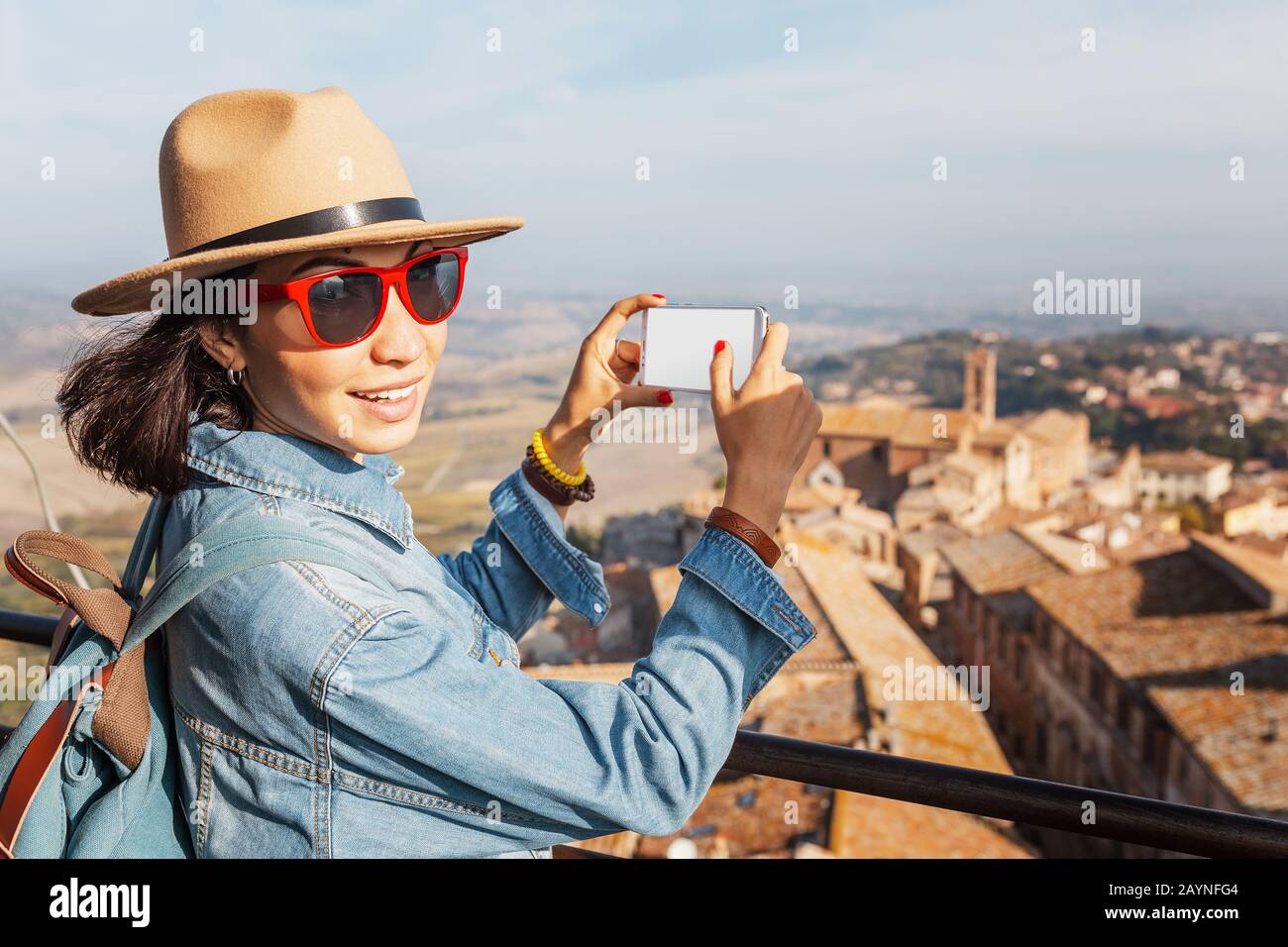 Felice donna turistica asiatica con smartphone nel centro storico di Montepulciano, Toscana. Vacanze e viaggi in Italia concetto Foto Stock