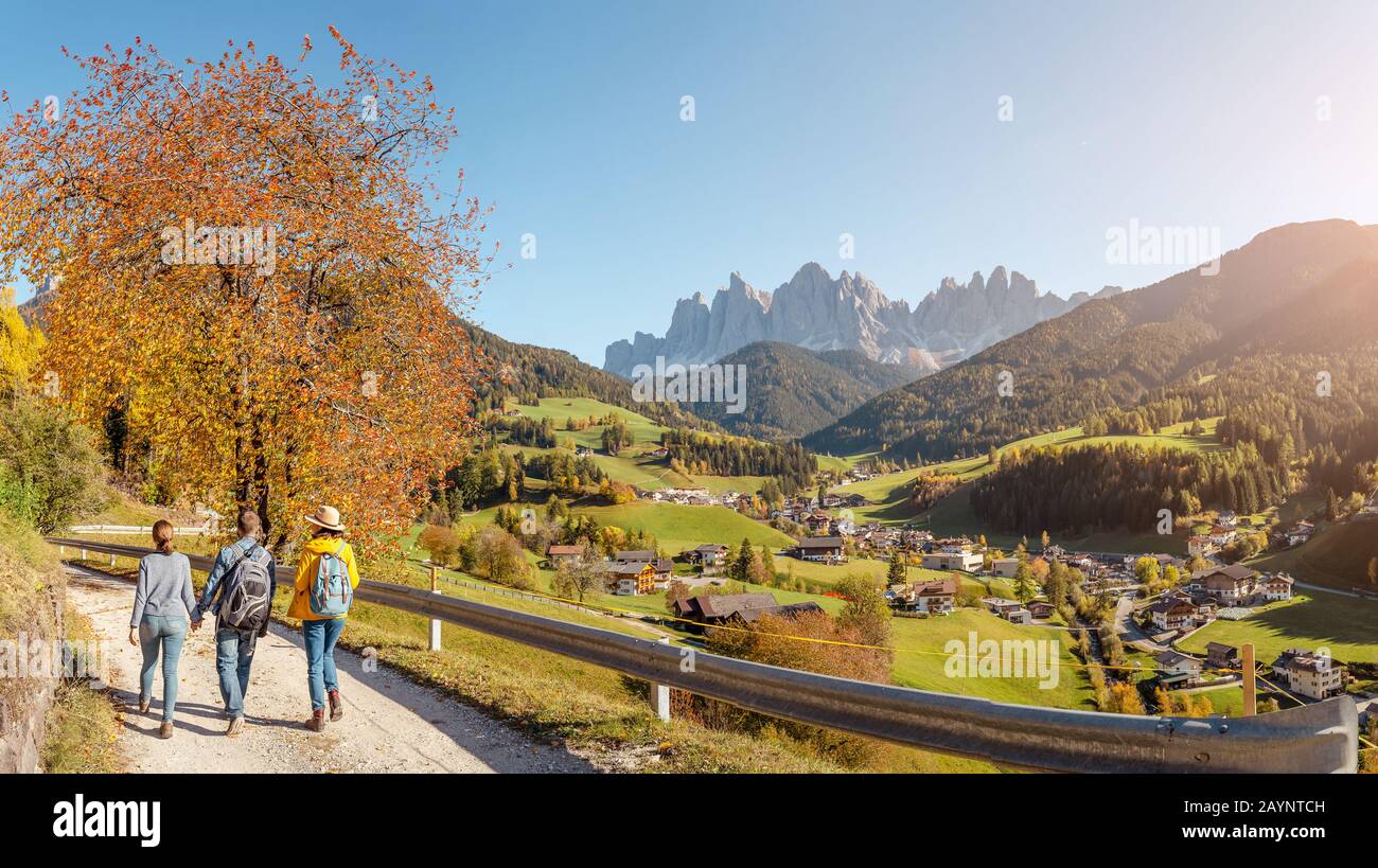 Tre amici attivi viaggiano nel villaggio di Santa Magdalena nella Valle di Funes, Alpi Italiane Foto Stock