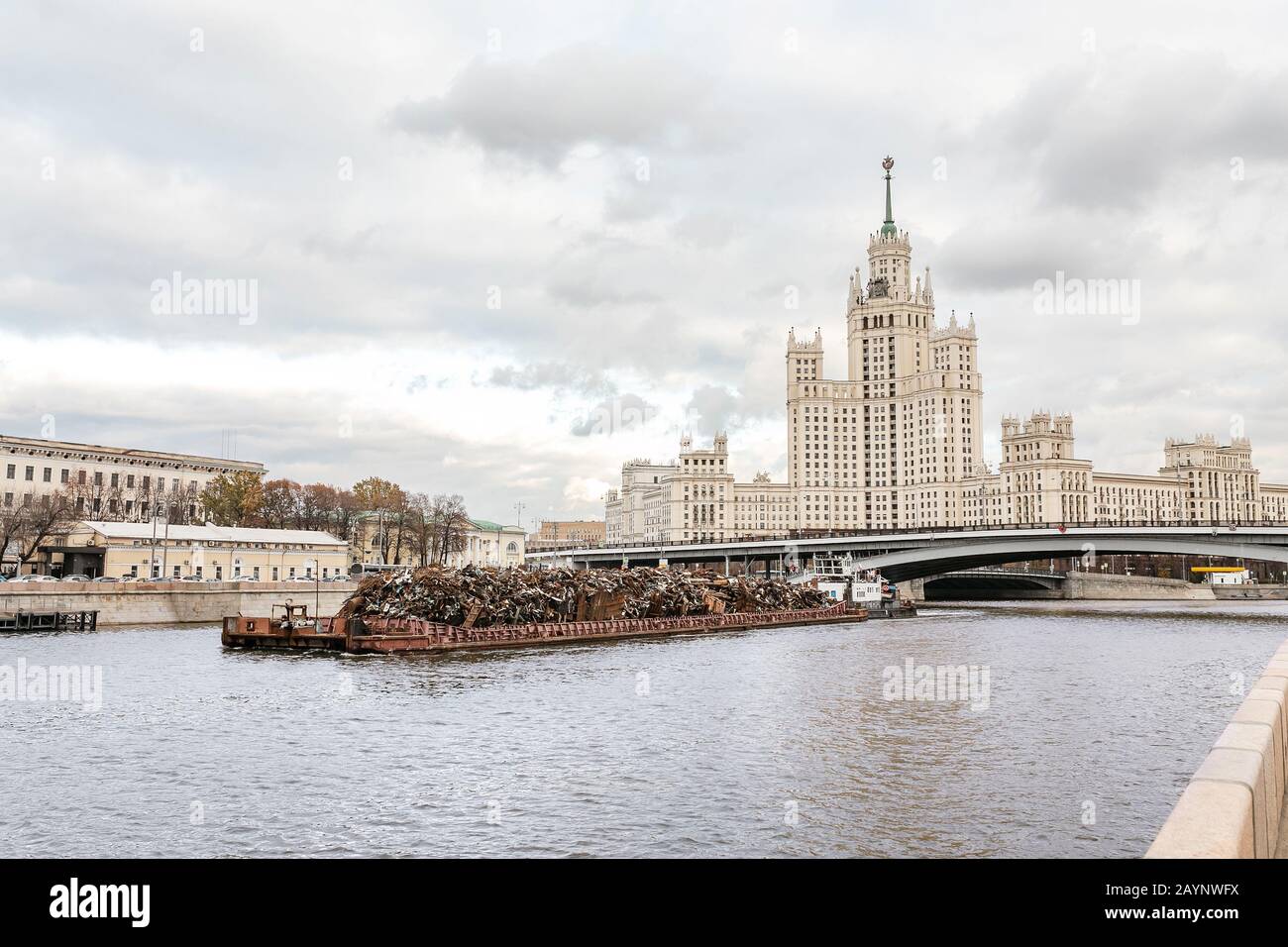 Alto edificio in stile Impero sull'argine Kotelnicheskaya a Mosca e grande nave da chiatta con metallo per il riciclaggio Foto Stock