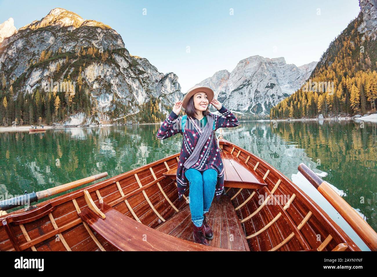 Felice donna asiatica seduta in barca vintage legno galleggiante e vela su un lago di Braies in Alpi italiane montagne, viaggio e sogno concetto di vacanza Foto Stock