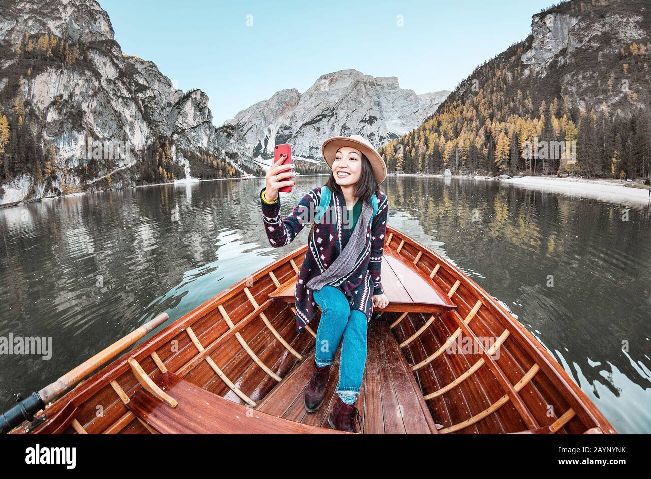 Felice donna asiatica prendere selfie con smartphone in una barca in un lago di montagna durante la stagione autunnale Foto Stock