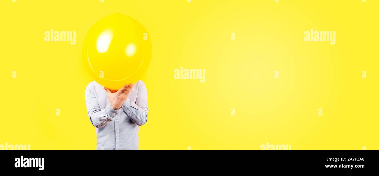 uomo che tiene palloncino giallo. Concetto di pensiero positivo, immagine su sfondo giallo, panoramica mock-up con spazio per il testo Foto Stock