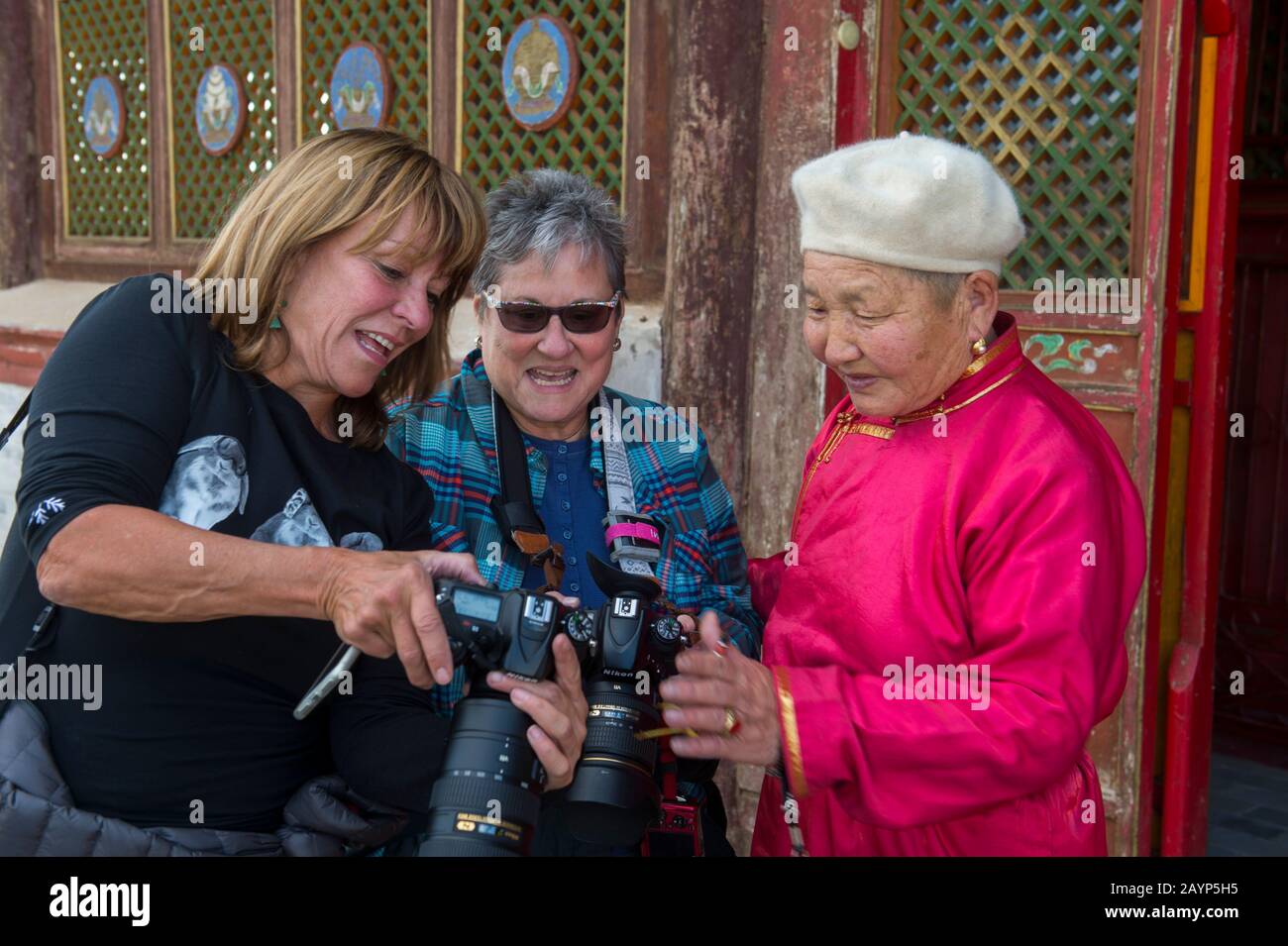 I turisti che mostrano le foto ad una donna mongola più anziana in abito tradizionale al monastero di Erdene Zuu a Kharakhorum (Karakorum), Mongolia. Foto Stock