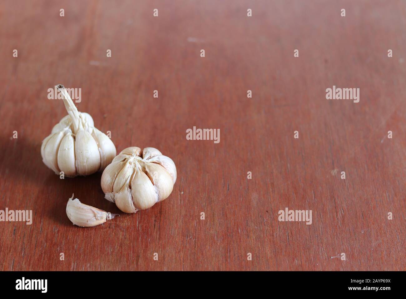 Bulbi d'aglio su uno sfondo di legno per mostrare il concetto di gastronomia, cucina ayurveda e medicina alternativa Foto Stock