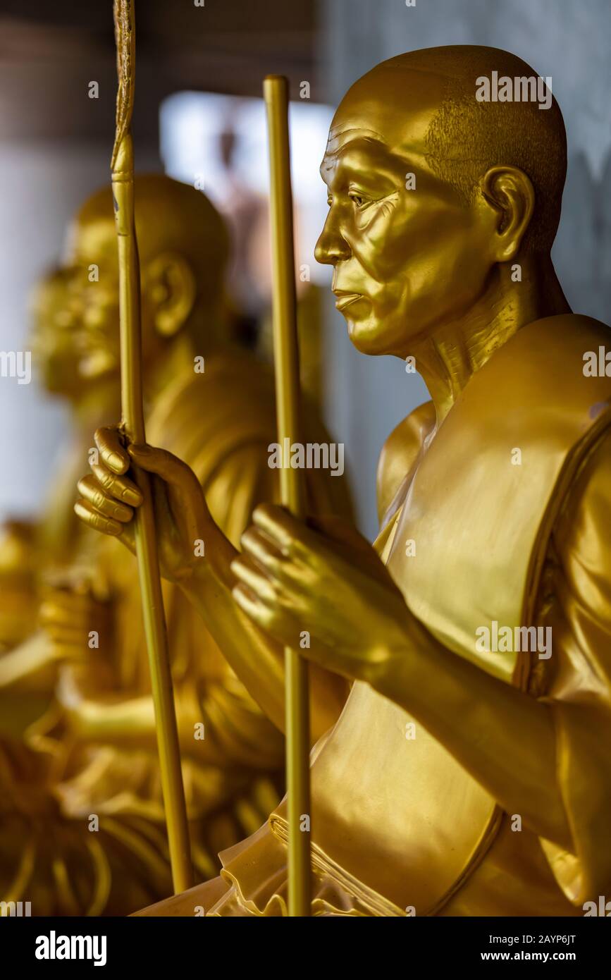 modelli buddisti dipinti d'oro e sculture in esposizione in thailandia in un tempio per la religione e adoratori che pregano per dèi e divinità. Foto Stock