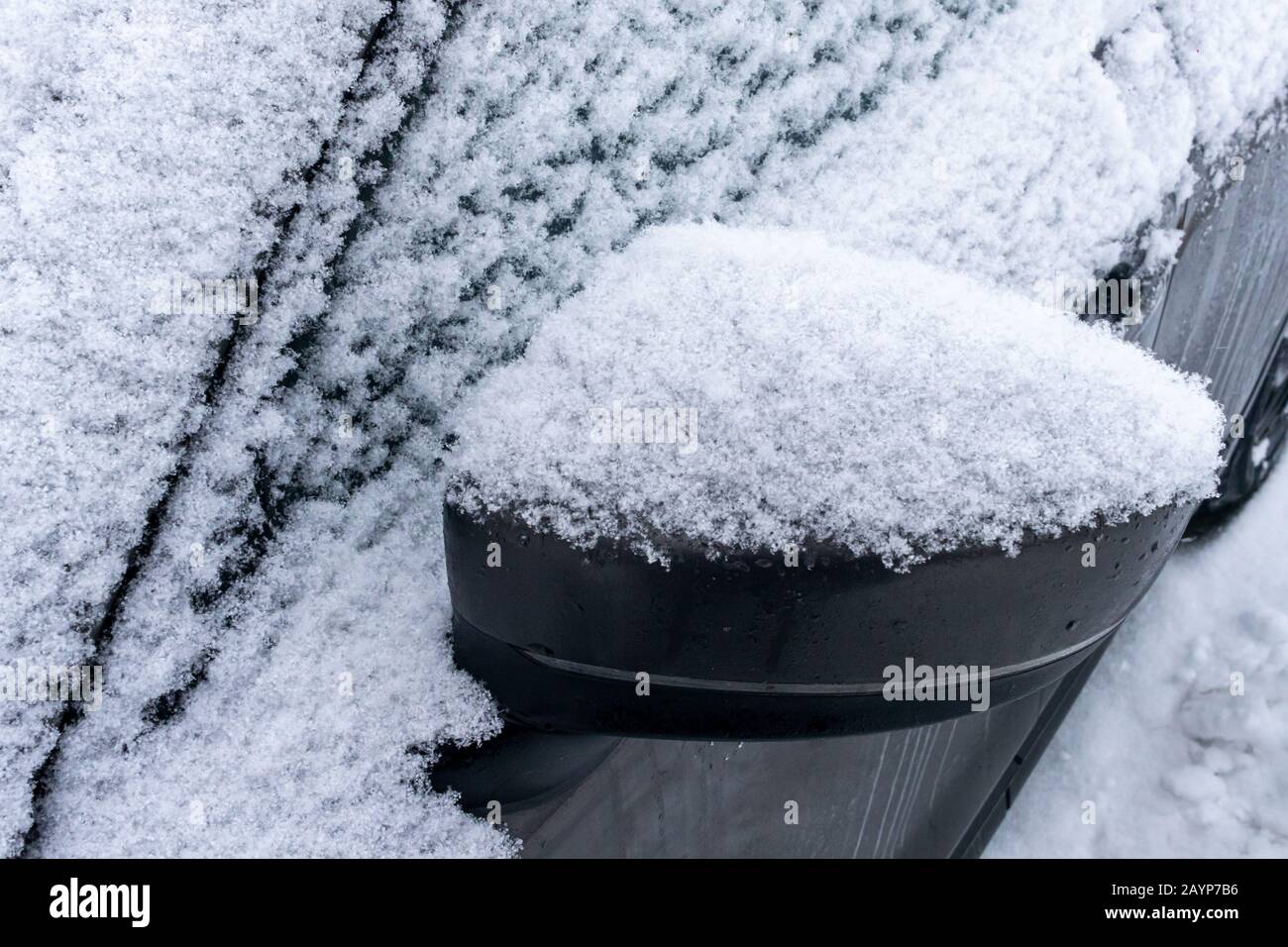 Lo specchio laterale montato su un'auto è coperto di neve in inverno dopo una fresca nevicata. Foto Stock