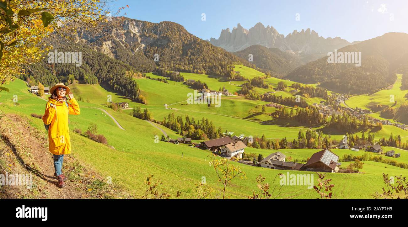 Felice donna asiatica godendo di una splendida vista nella Val di Funes nelle Alpi Dolomiti in Italia durante la stagione autunnale Foto Stock