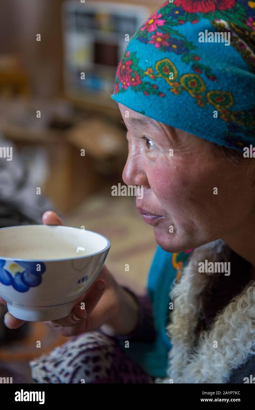 Primo piano di una donna kazaka che beve il tradizionale suutei thai (tè al latte) nella cucina del campo d'inverno (casa) nella Valle Sagsai nell'Altai Mou Foto Stock