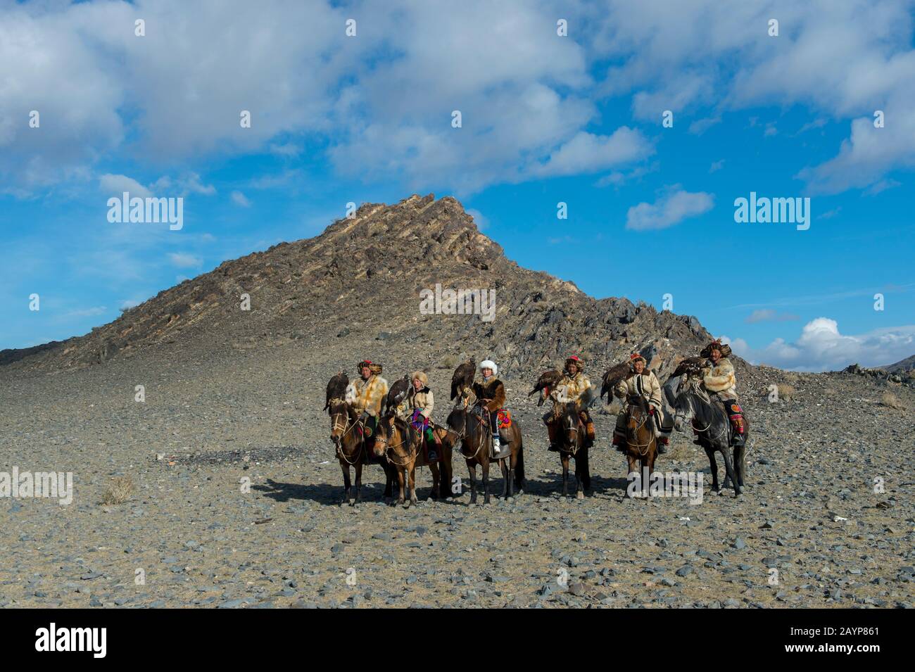 Un gruppo di cacciatori di aquila kazaka e le loro aquile d'oro a cavallo sulla strada per il Festival dell'aquila d'oro vicino alla città di Ulgii (Ölgii) nella baia Foto Stock