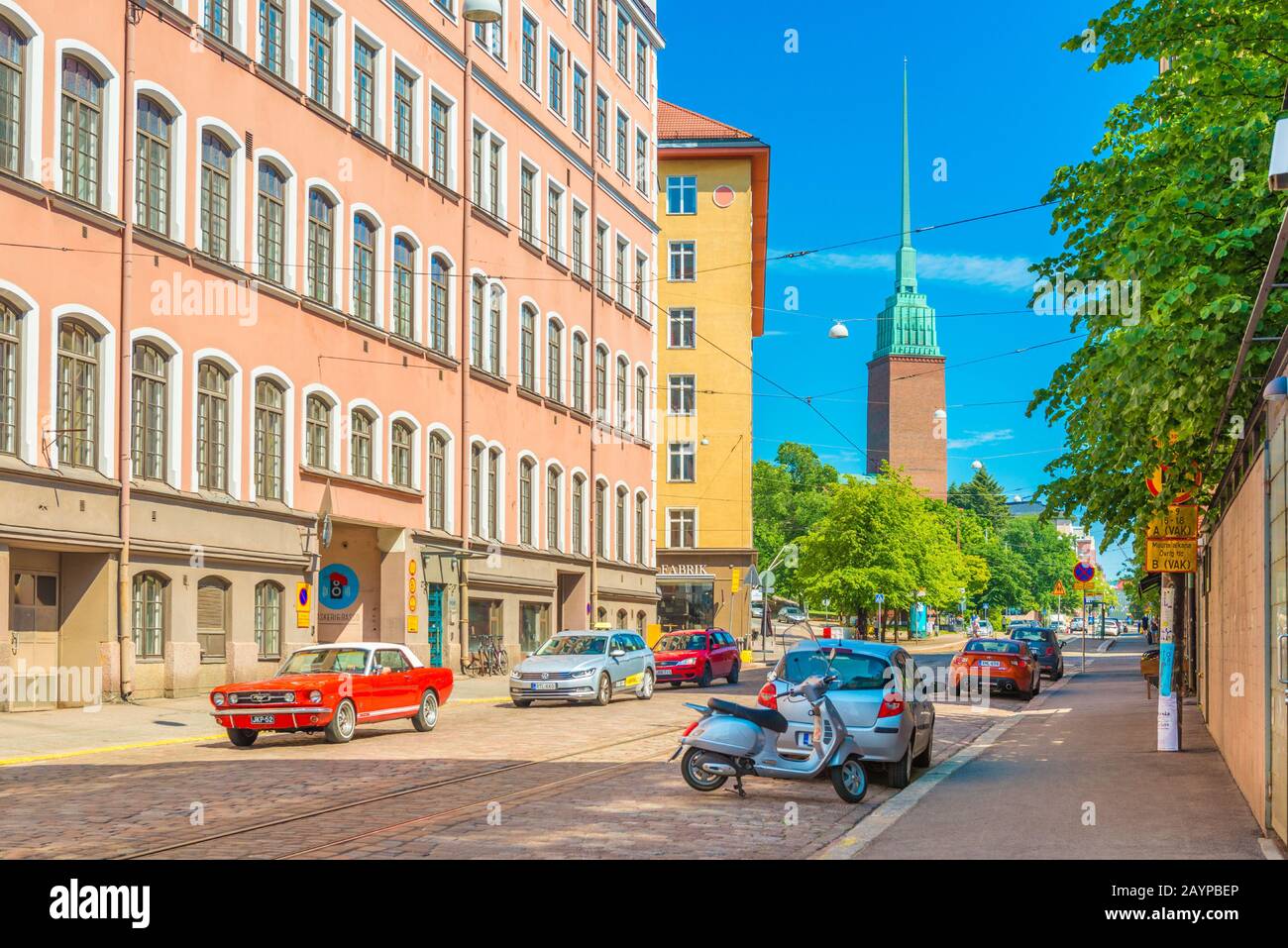 Helsinki - Giugno 2019, Finlandia: Una strada con traffico automobilistico, la Chiesa di Mikael agricola e colorati edifici residenziali Foto Stock