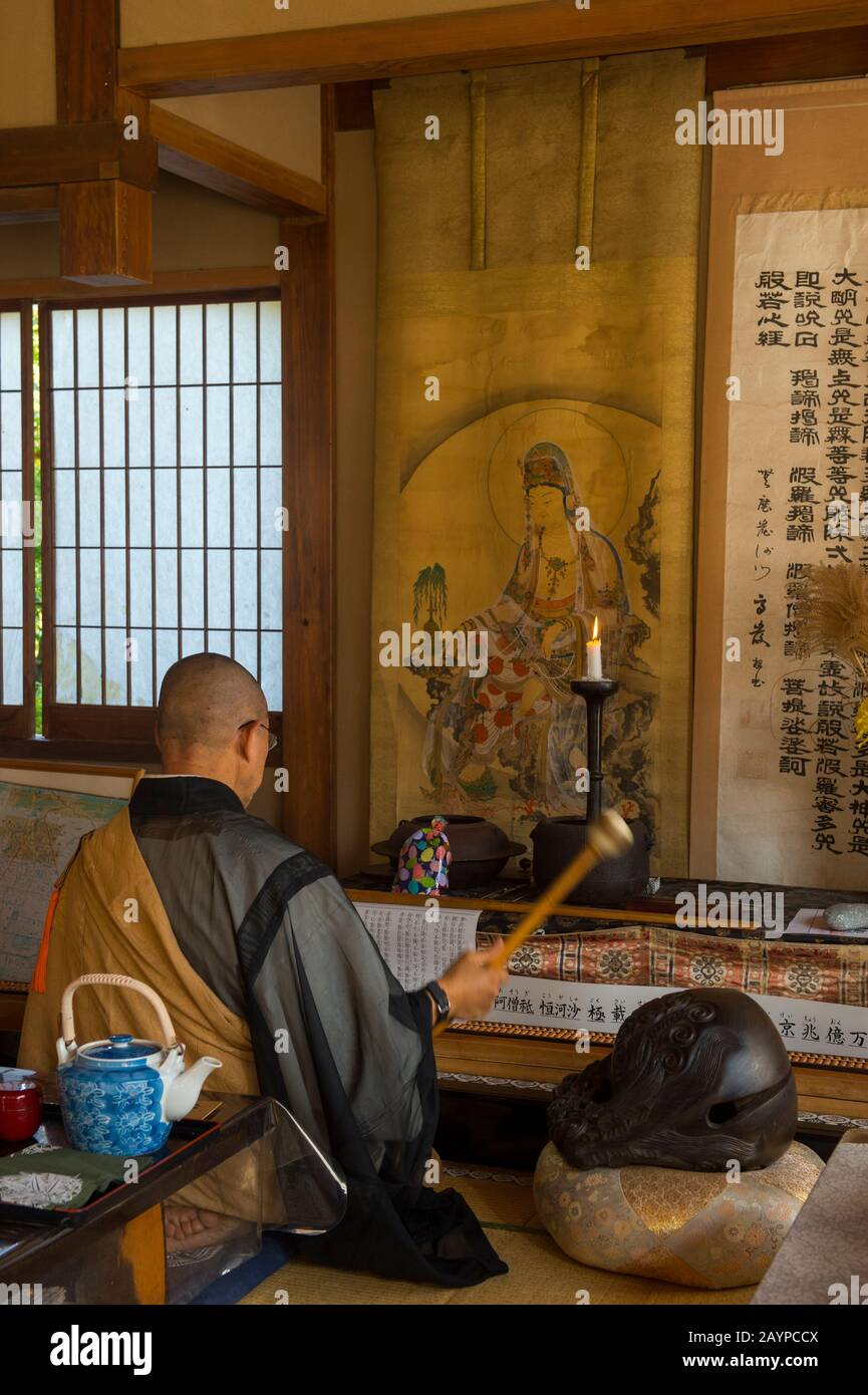 Un monaco al tempio di Senkoji nella foresta sopra il fiume Katsura a Kyoto, il Giappone sta suonando una campana durante la sua conferenza sul Buddismo Zen e meditando Foto Stock