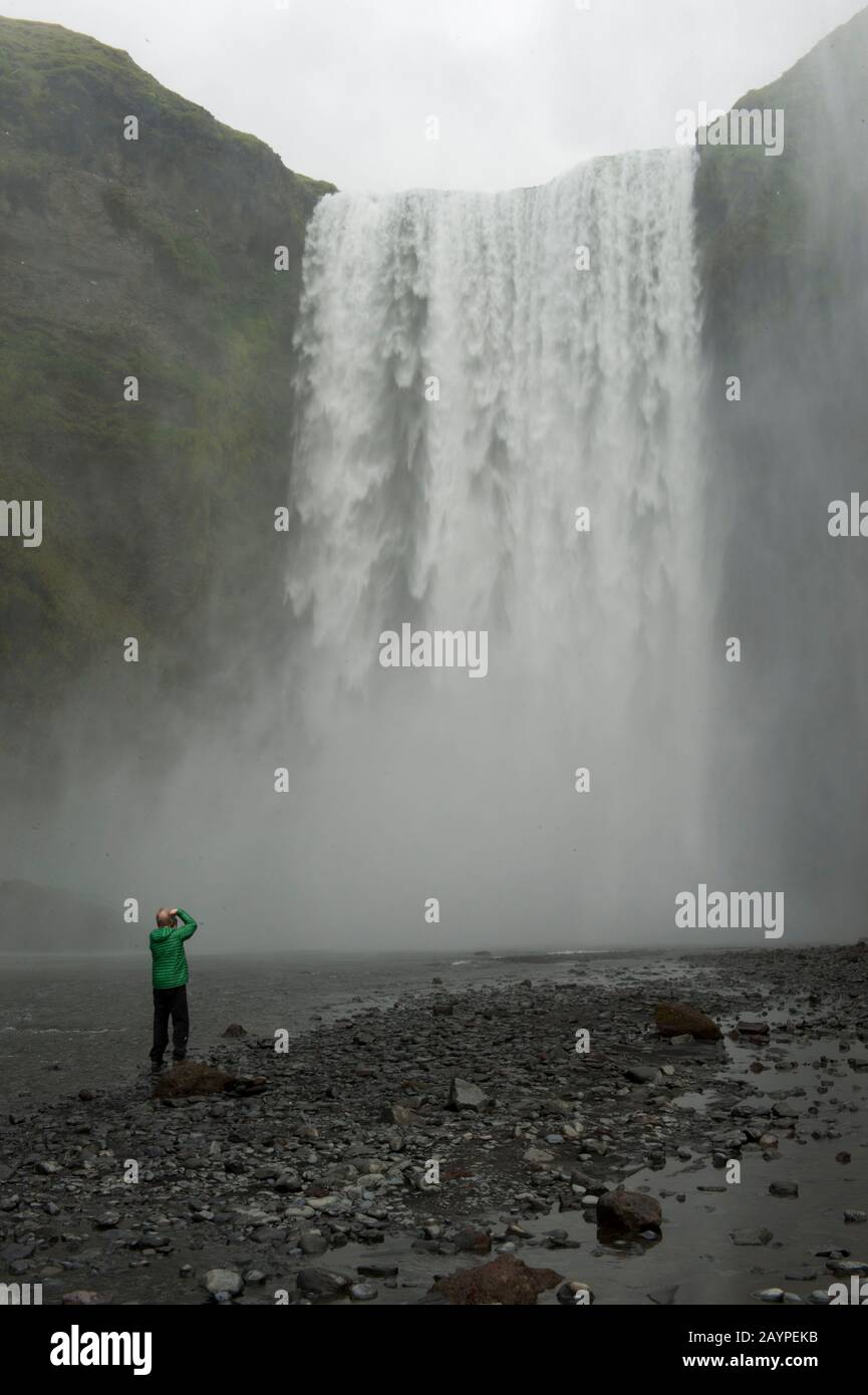 Turistico allo Skogafoss, una delle più grandi cascate del sud dell'Islanda, con una larghezza di 15 metri e una caduta di 60 metri. Foto Stock