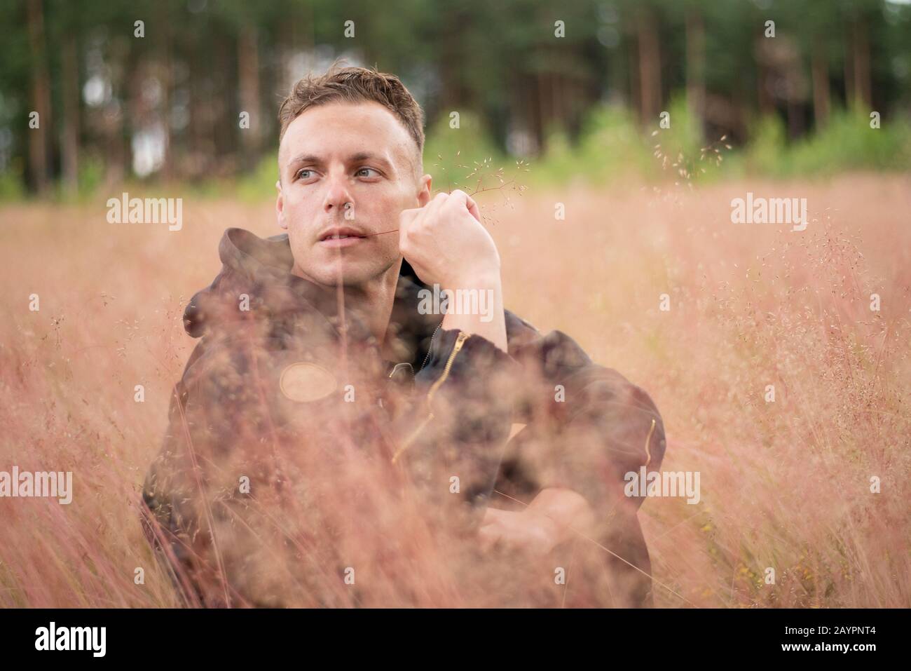 L'uomo siede in un campo spesso, e pensa. Foto Stock