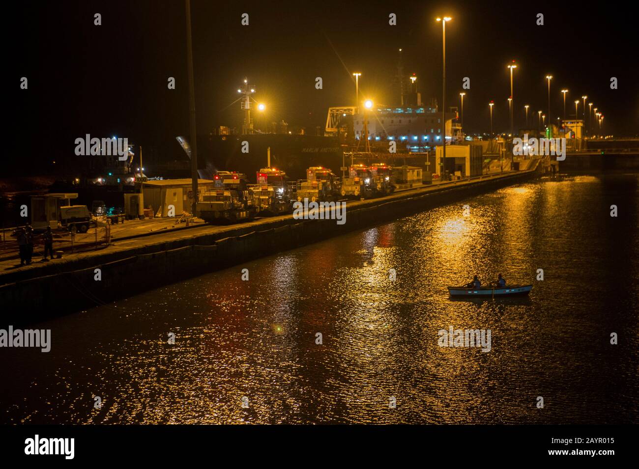 Uomini di linea in una barca di fila che ottiene le linee di una nave di notte nel canale di Panama alle chiuse di Miraflores vicino alla città di Panama, Panama. Foto Stock