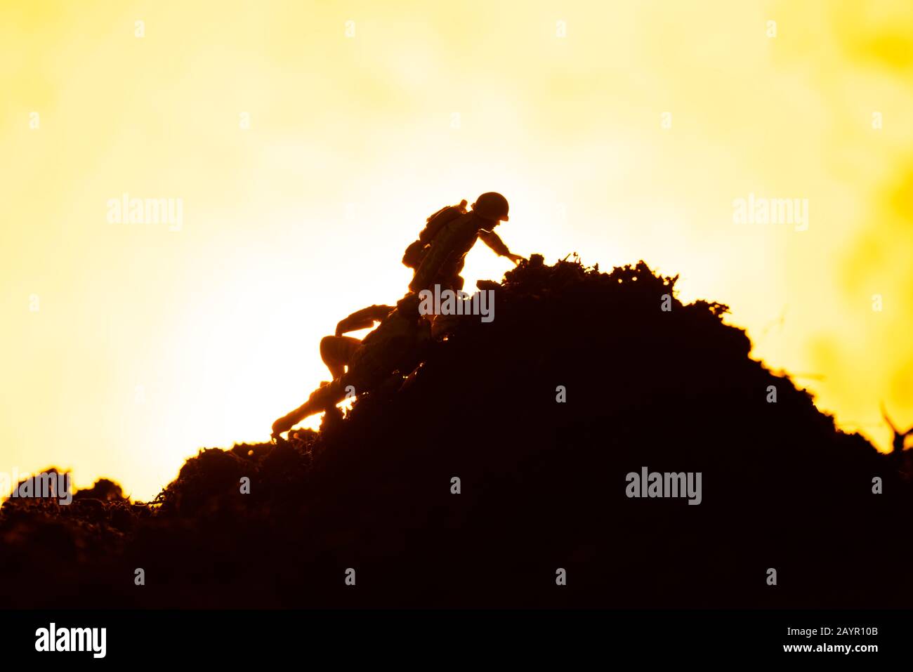 Scena di battaglia con i guerrieri giocattolo sul campo di battaglia e fuoco su sfondo giallo Foto Stock