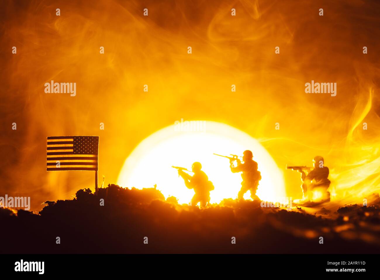Scena di battaglia di soldati giocattolo, bandiera americana e fuoco con tramonto sullo sfondo Foto Stock