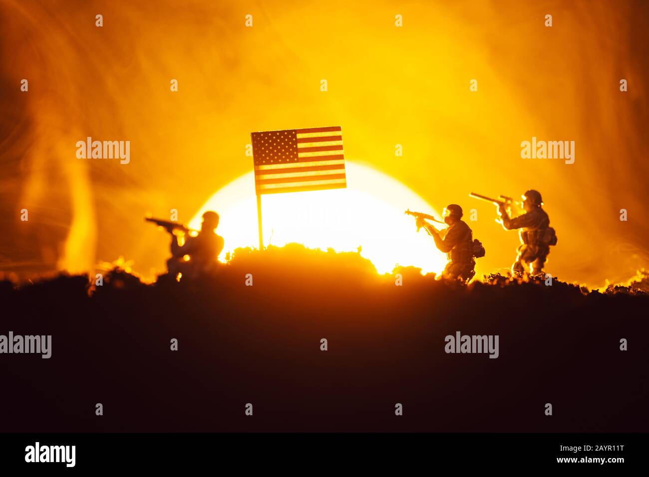 Scena di battaglia con i guerrieri giocattolo vicino alla bandiera americana in fumo con tramonto sullo sfondo Foto Stock
