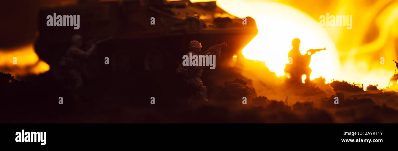 Scena di battaglia con guerrieri giocattolo, canotta e fuoco con tramonto sullo sfondo, scatto panoramico Foto Stock