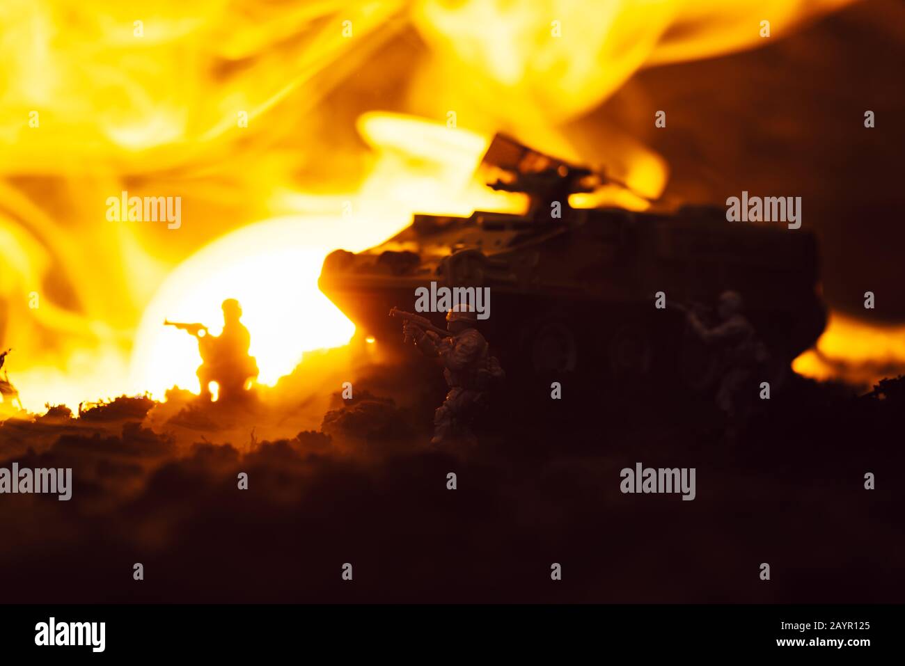 Soldati giocattolo con serbatoio, fuoco e tramonto su sfondo nero, scena di battaglia Foto Stock