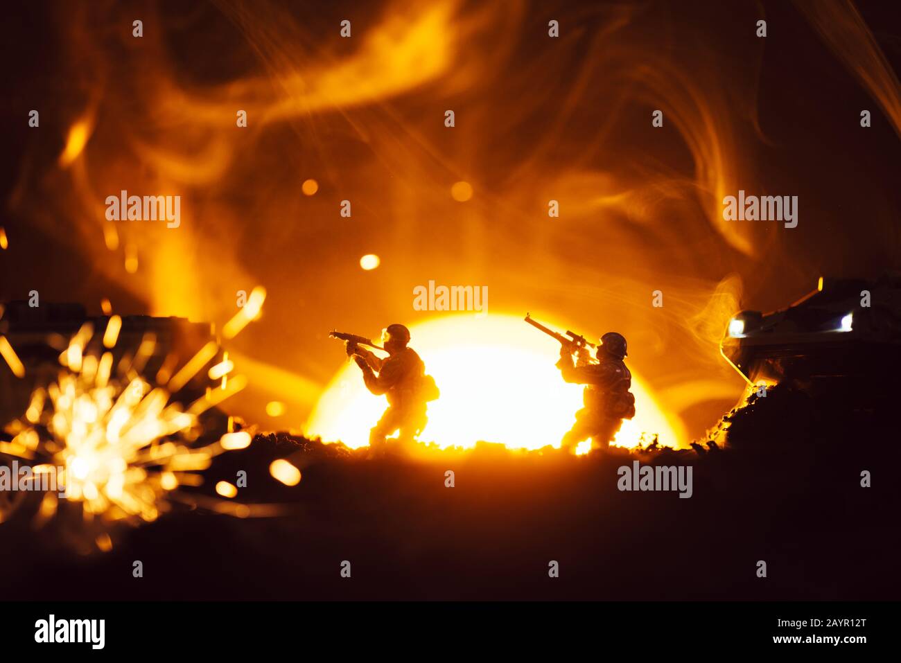 Fuoco selettivo di guerrieri giocattolo con serbatoi vicino esplosione e fumo con tramonto sullo sfondo Foto Stock