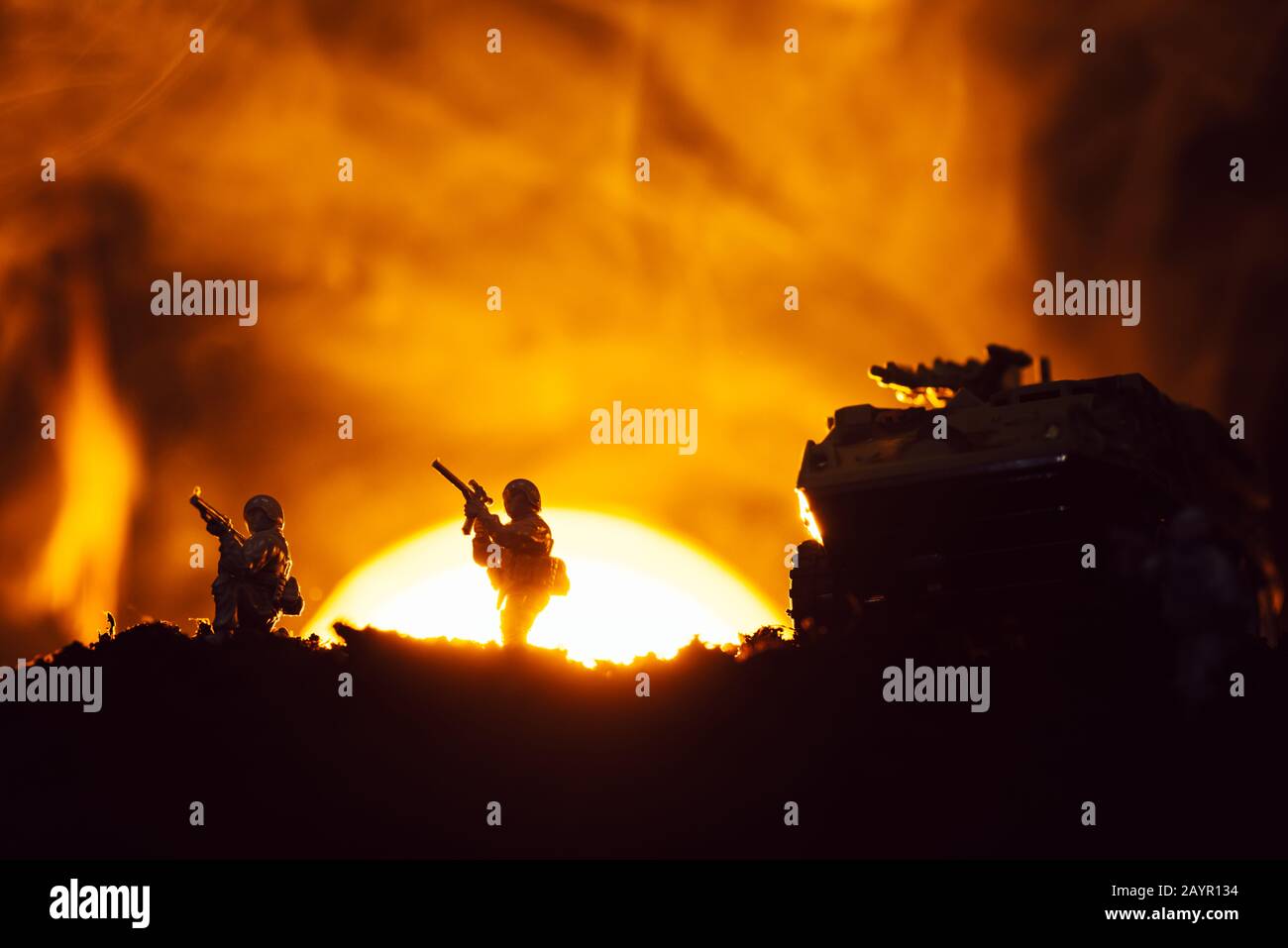 Silhouette di guerrieri giocattolo e canotta sul campo di battaglia con tramonto e fuoco sullo sfondo Foto Stock