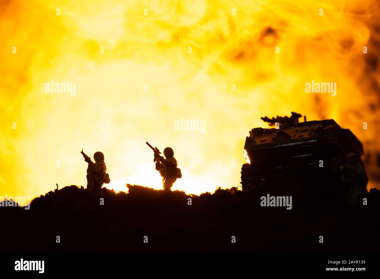 Scena di battaglia con silhouette di tank giocattolo e soldati con fuoco sullo sfondo Foto Stock