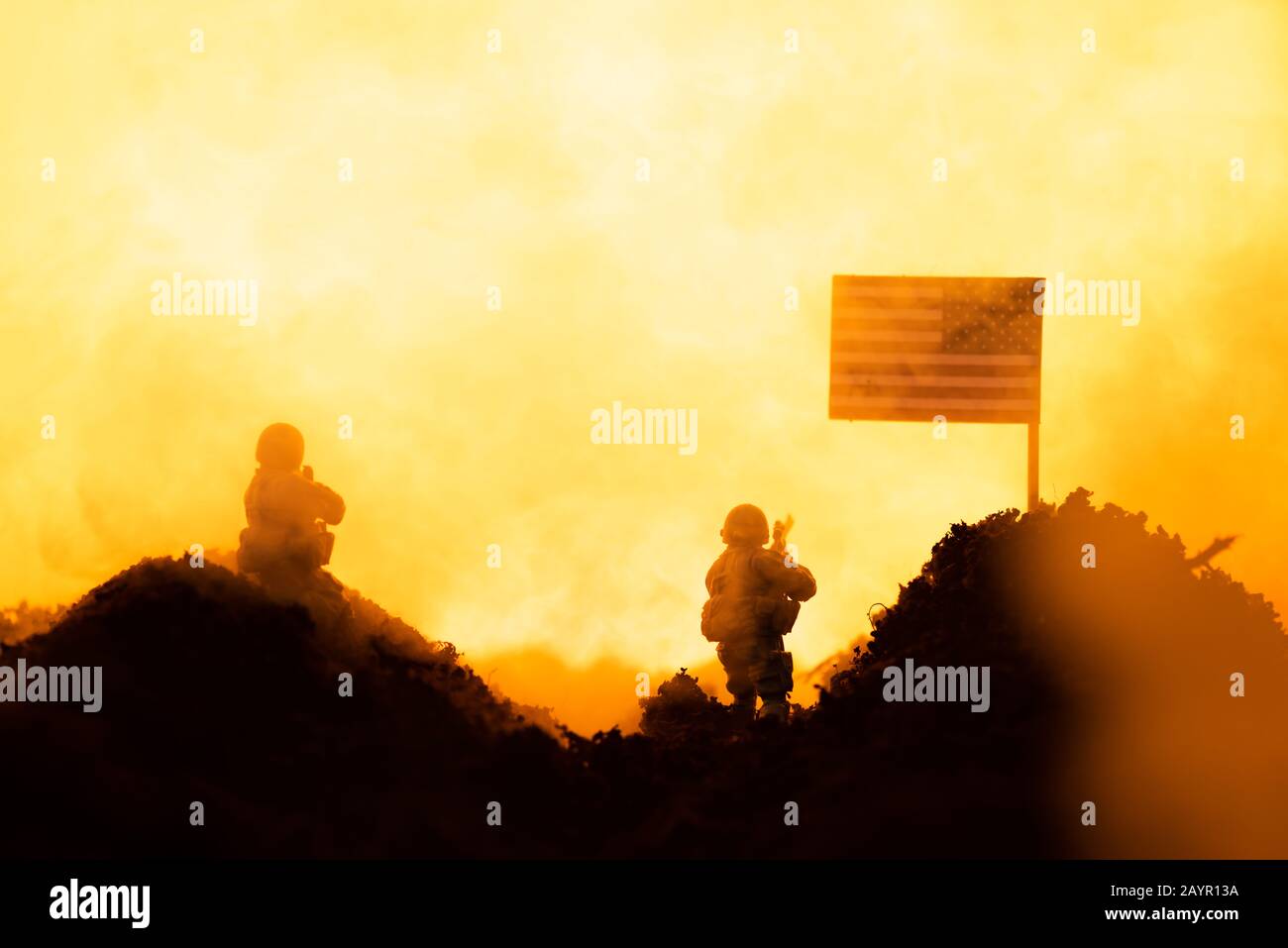 Scena di battaglia con soldati giocattolo vicino bandiera americana con fuoco sullo sfondo Foto Stock