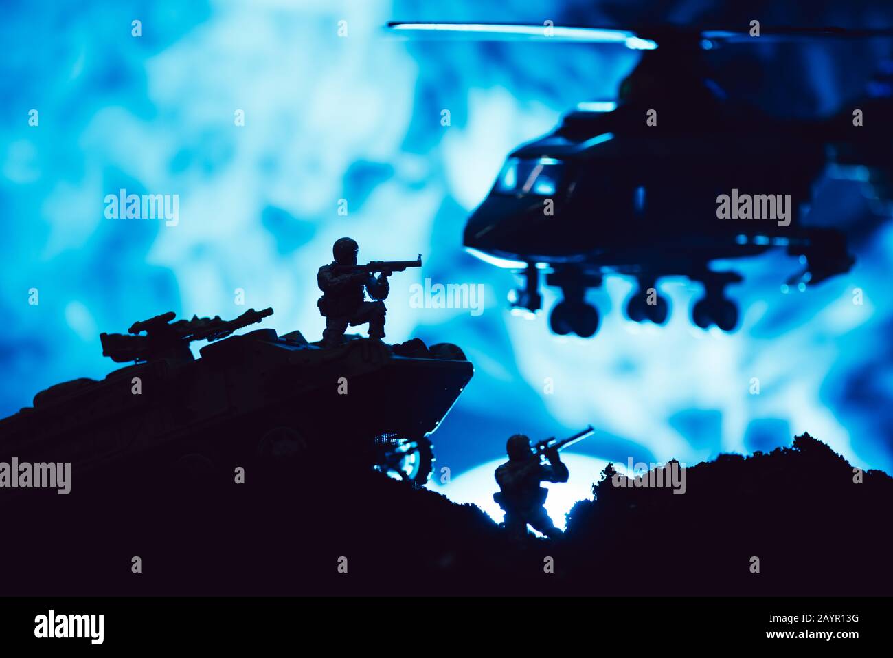 Scena di battaglia con guerrieri giocattolo, canotta ed elicottero con fumo su sfondo blu Foto Stock