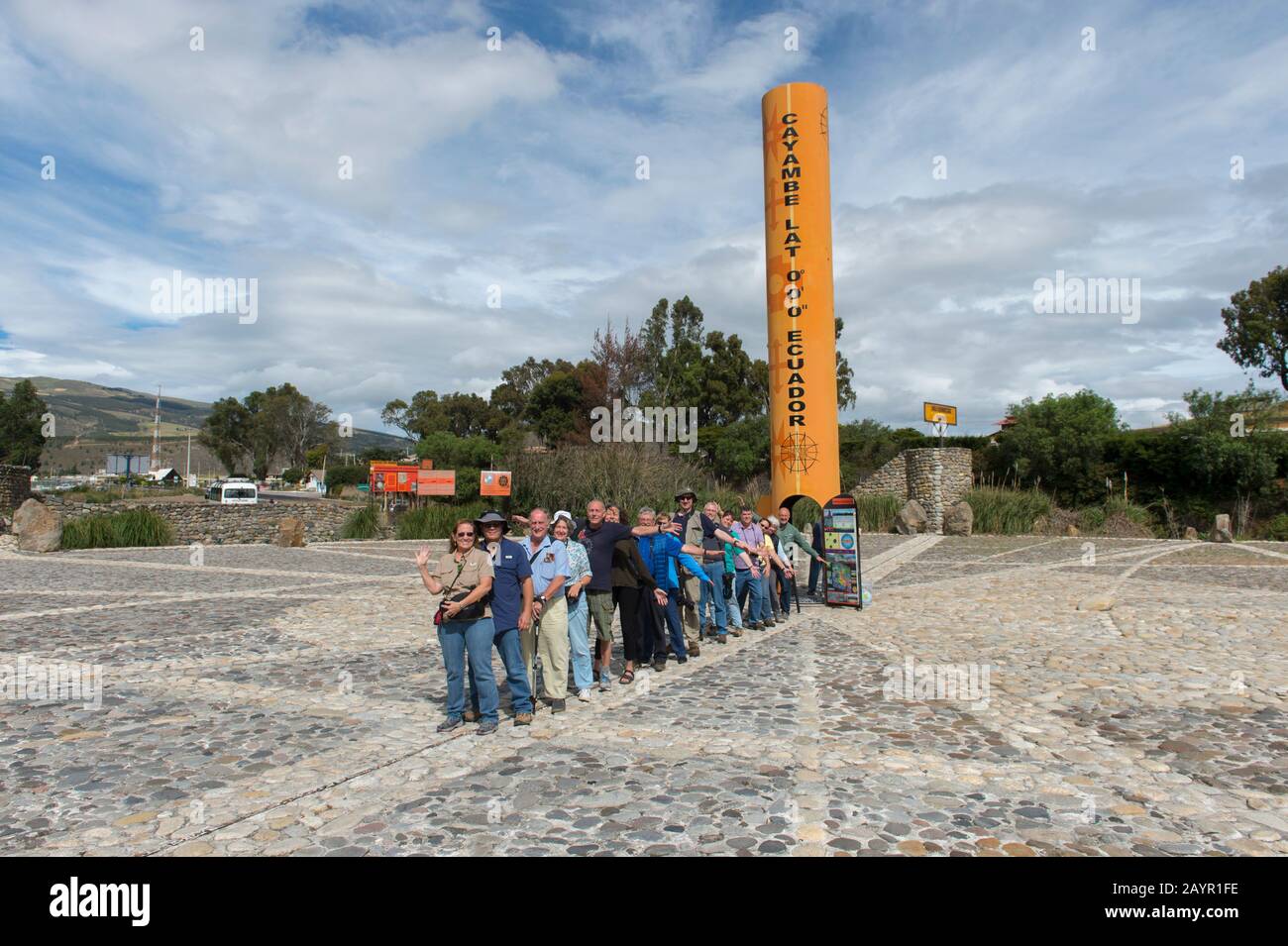 Un gruppo di tour è in piedi con un piede nell'emisfero settentrionale e l'altro piede nell'emisfero meridionale presso il monumento equatore Quitsato e s. Foto Stock