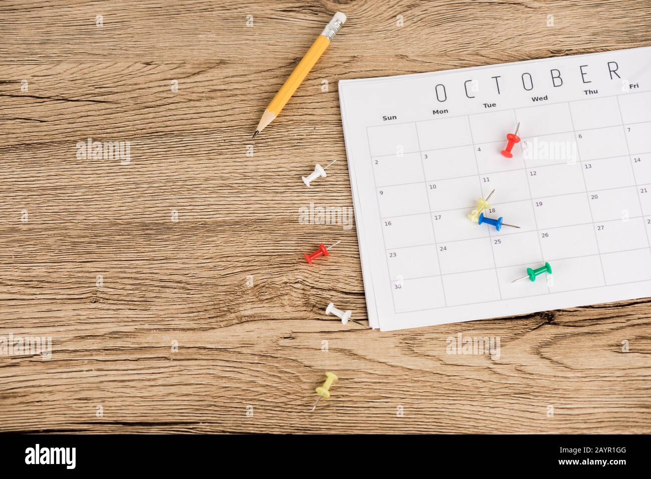 Vista dall'alto della matita, dei perni da ufficio e del calendario di ottobre sulla superficie in legno Foto Stock