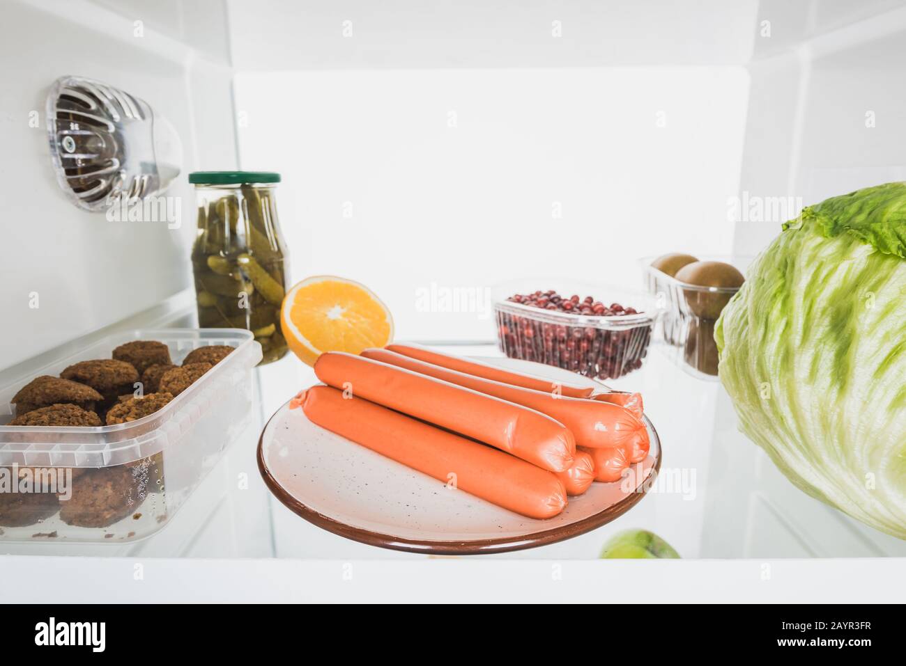 Salsicce, frutta fresca e cavolo sul ripiano frigo isolato su bianco, immagine stock Foto Stock