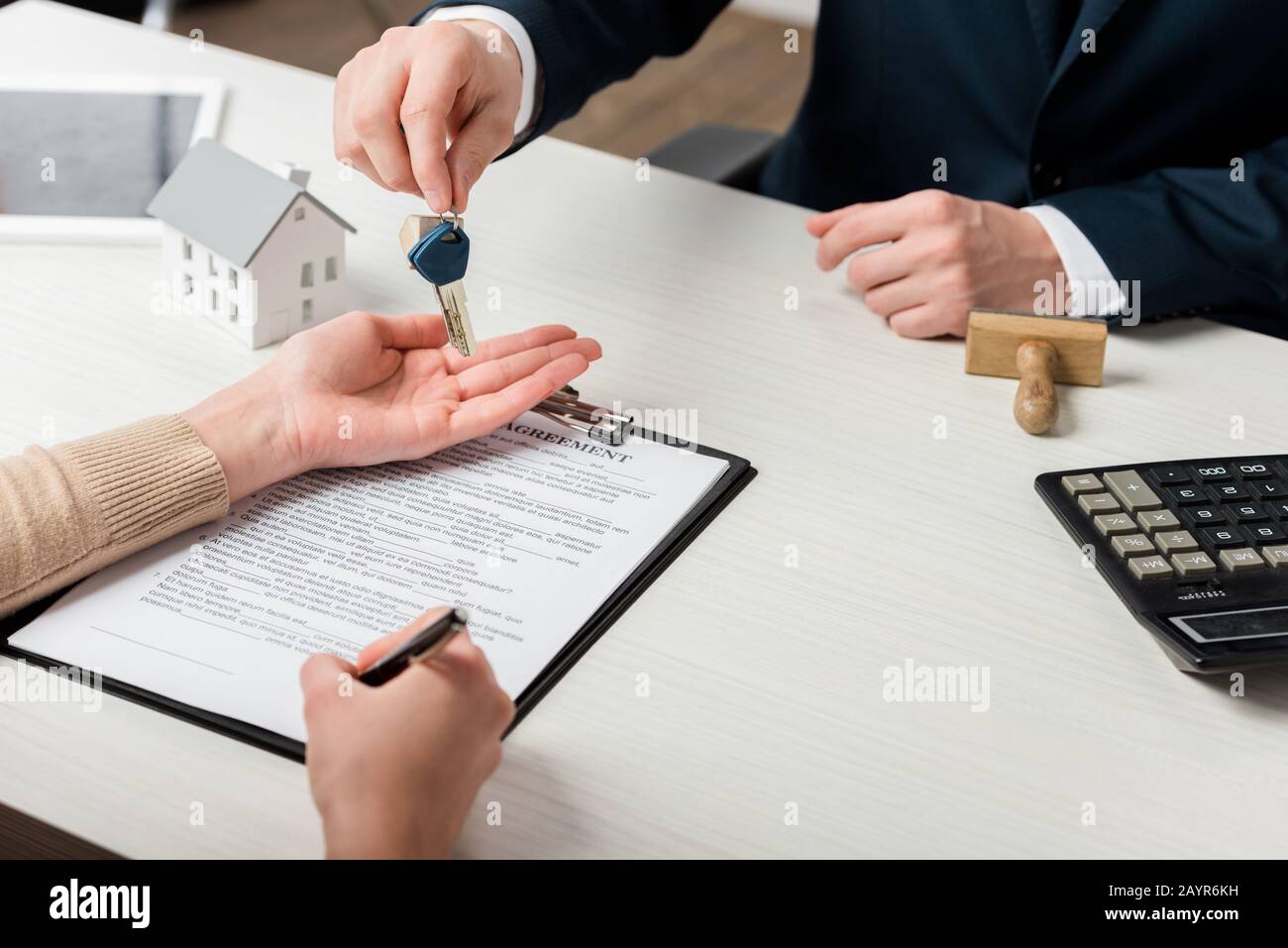 vista ritagliata del realtor che dà la chiave alla donna che firma il contratto, concetto di leasing Foto Stock