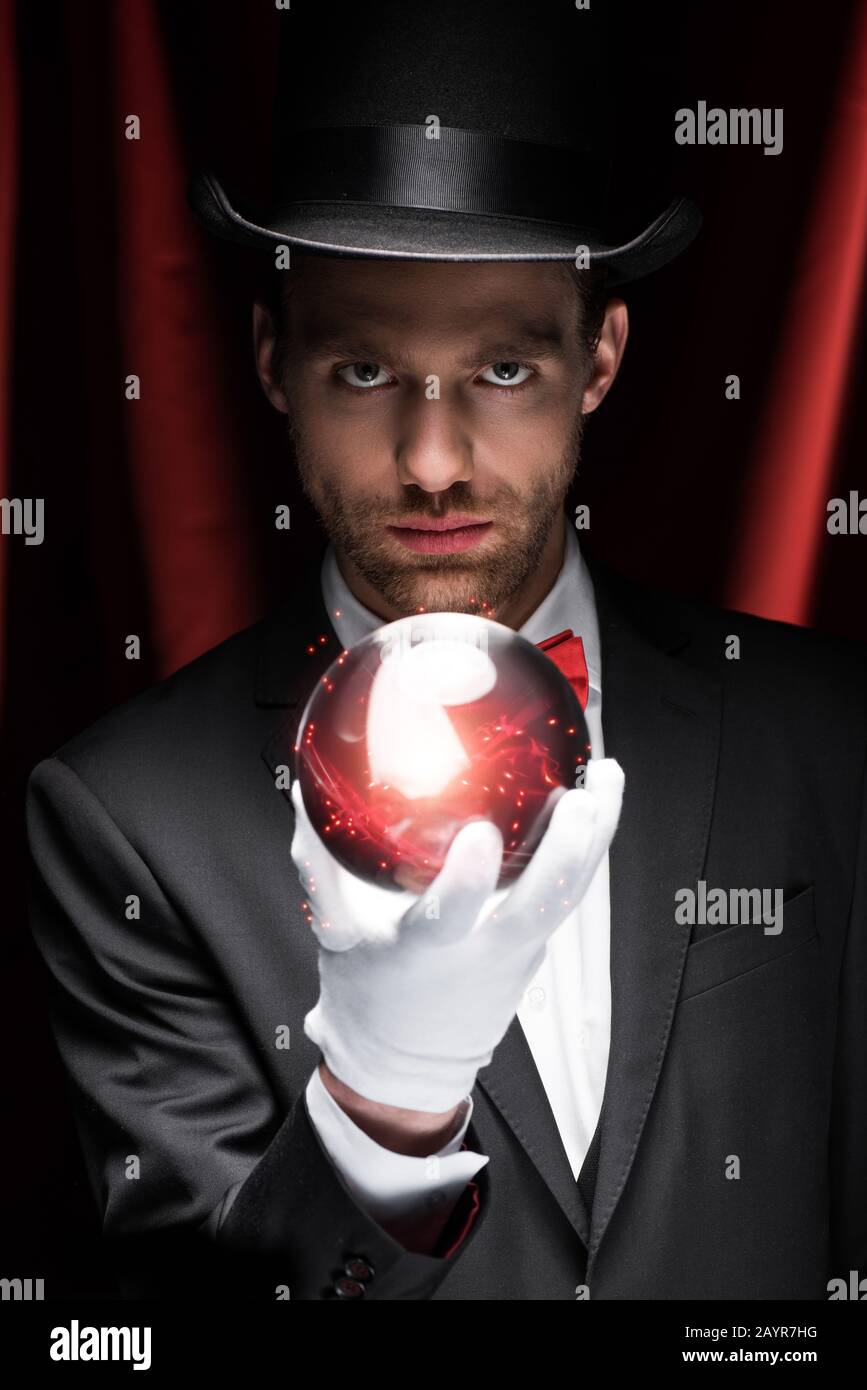 mago professionista con palla magica rossa in circo con tende rosse Foto Stock