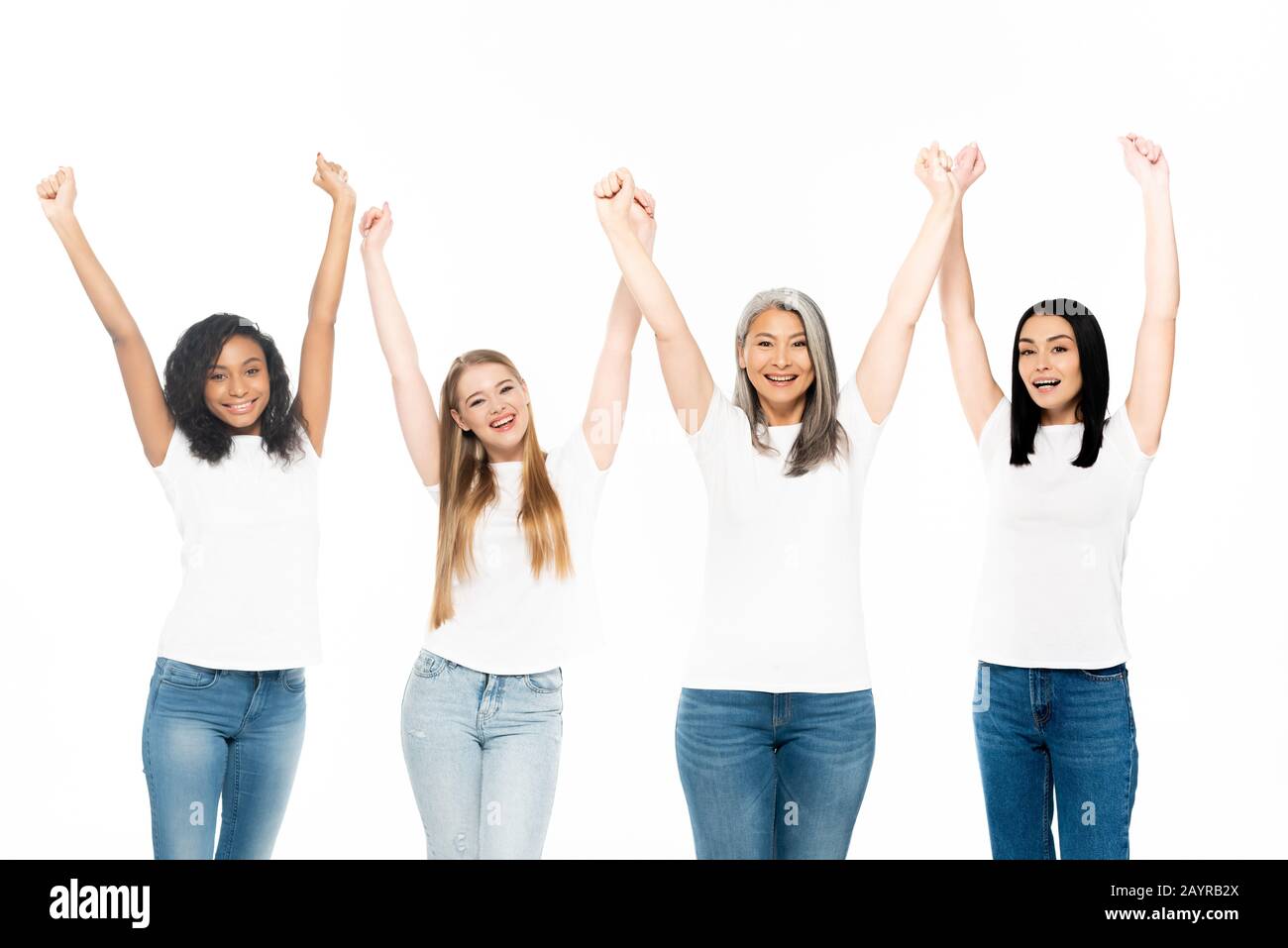 donne multiculturali felici in jeans denim in piedi con le mani sopra la testa isolato su bianco Foto Stock