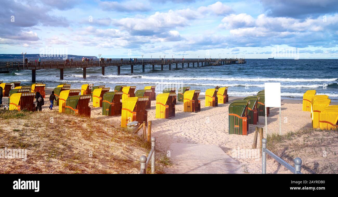 Spiaggia di sabbia e tradizionali sedie da spiaggia di legno sull'isola di Rügen, Germania settentrionale. Sullo sfondo il ponte-mare. Foto Stock