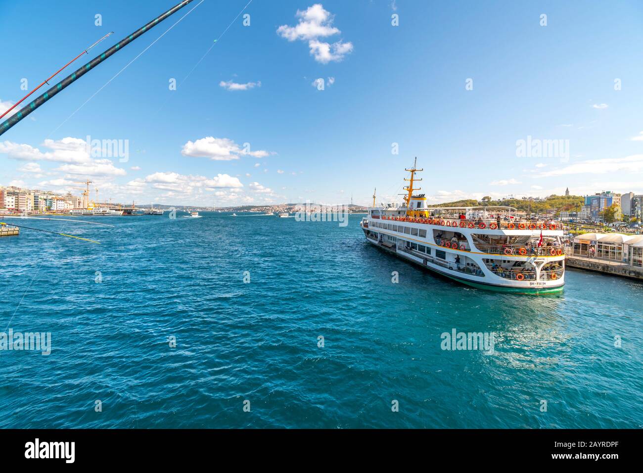 I pali da pesca e la linea si affacciano sul fiume Bosforo dal Ponte Galata mentre un tour in barca passa a Istanbul, Turchia. Foto Stock