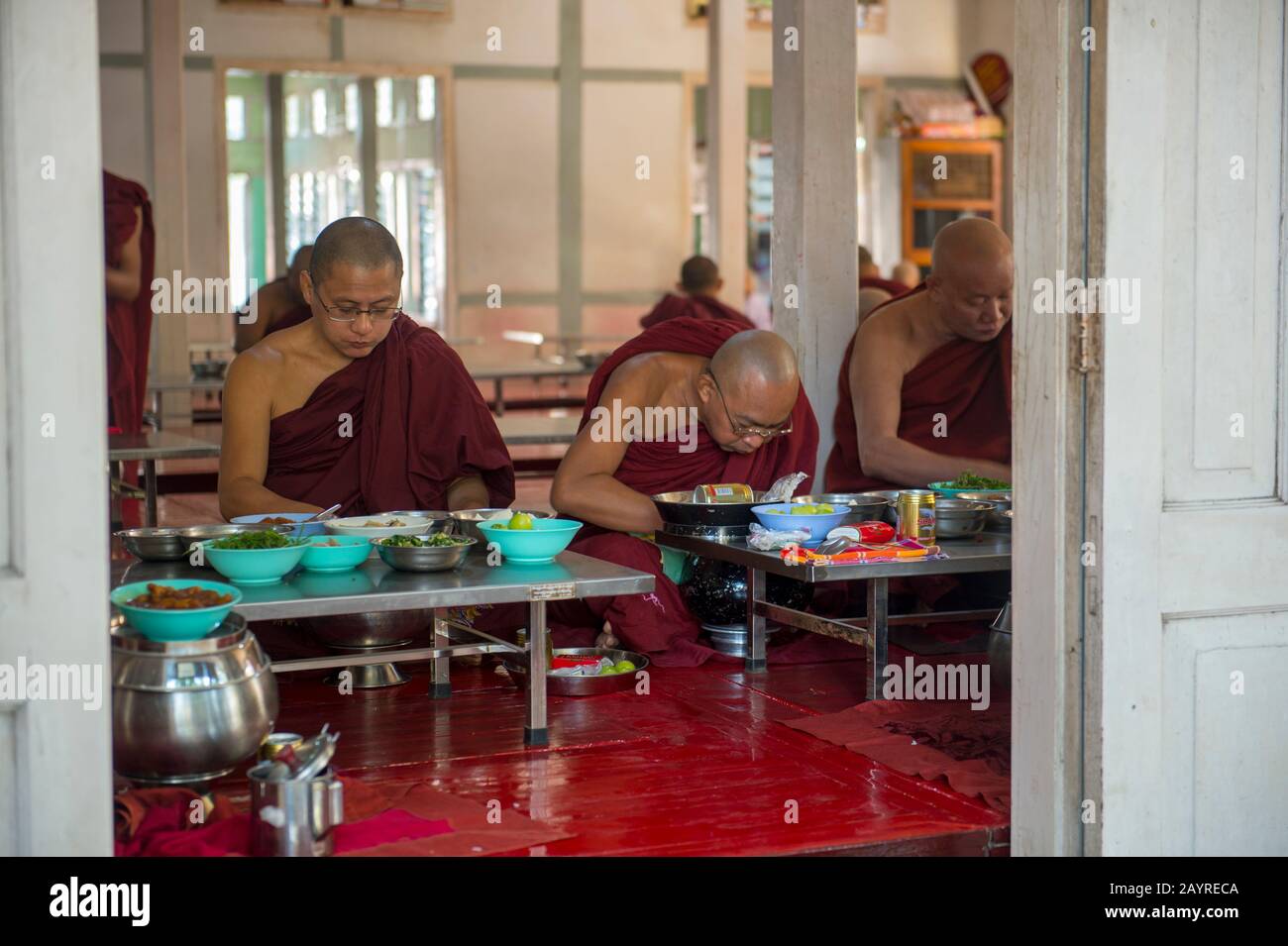 Monaci buddisti che mangiano dopo aver ricevuto le elemosine (pasto) al monastero di Mahagandayon a Mandalay, Myanmar. Foto Stock