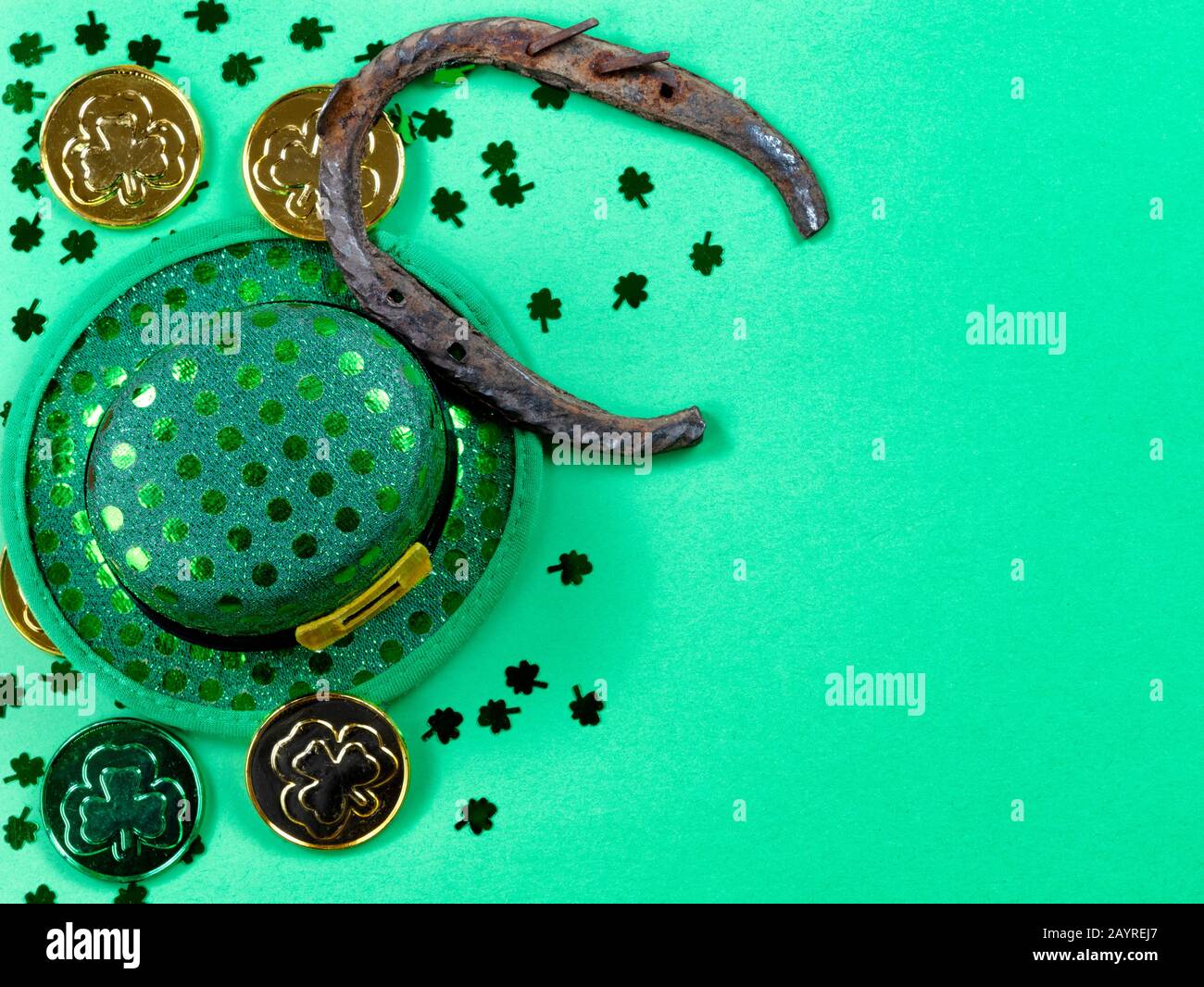 Giornata di San Patrizio con il confine di scogli, ferro di cavallo e monete d'oro su sfondo verde con spazio copia Foto Stock