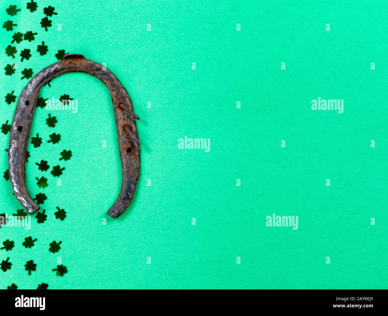 Giornata di San Patrizio con il confine di scogli e ferro di cavallo arrugginito su sfondo verde con spazio copia Foto Stock