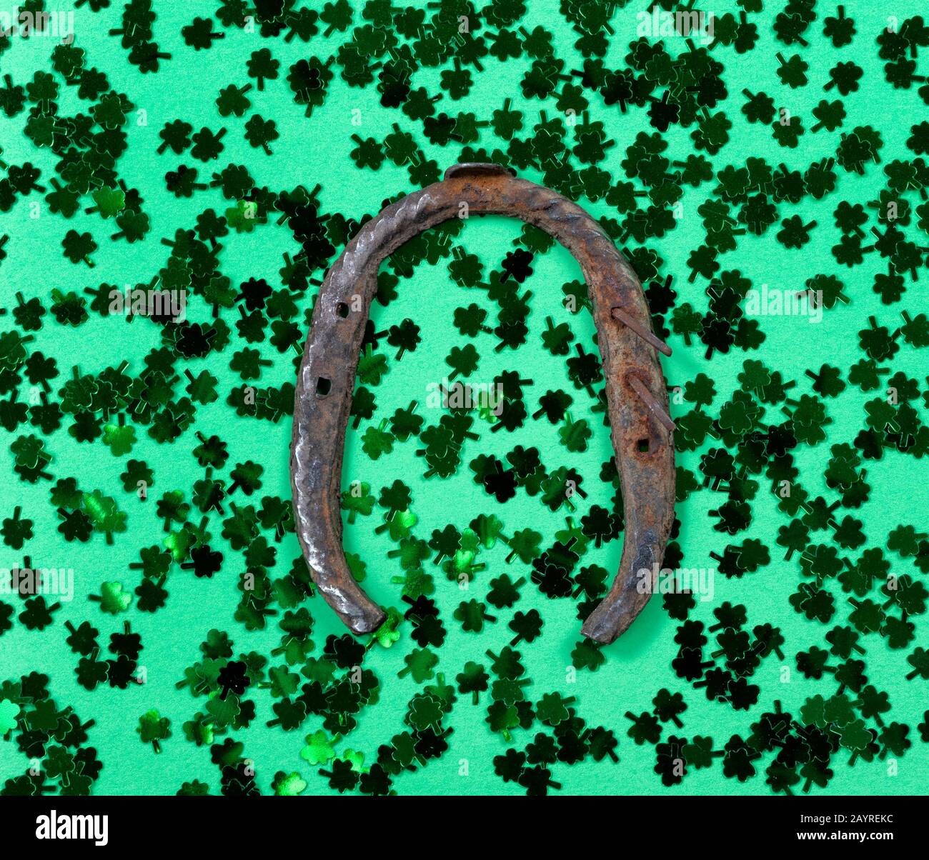 Giornata di San Patrizio con scogli e ferro di cavallo arrugginito su sfondo verde in formato cornice piena Foto Stock