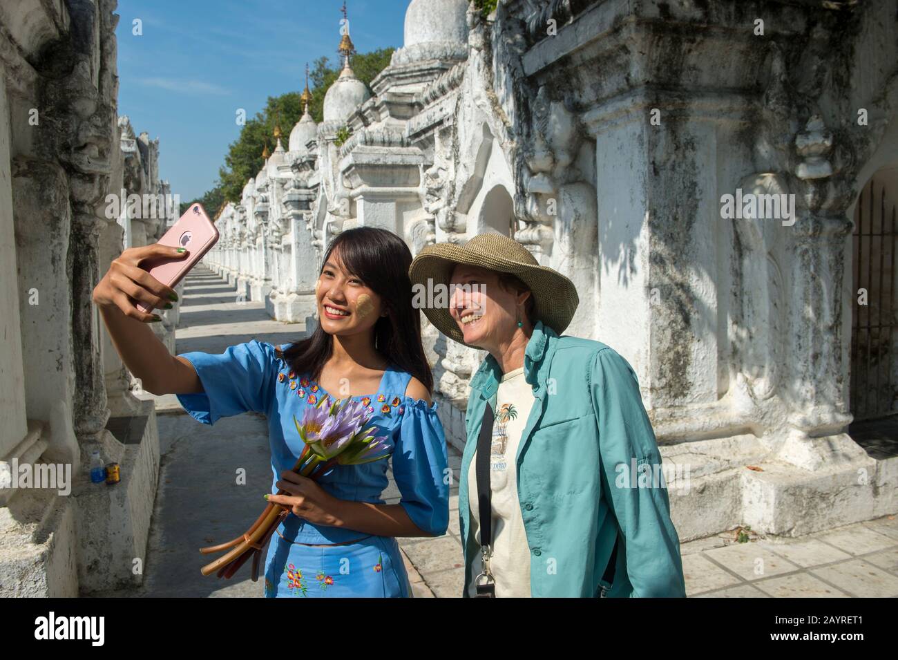 Una giovane donna locale sta prendendo un selfie cellulare con un turista alla Pagoda di Kuthodaw sulla collina di Mandalay, Mandalay, Myanmar. Foto Stock