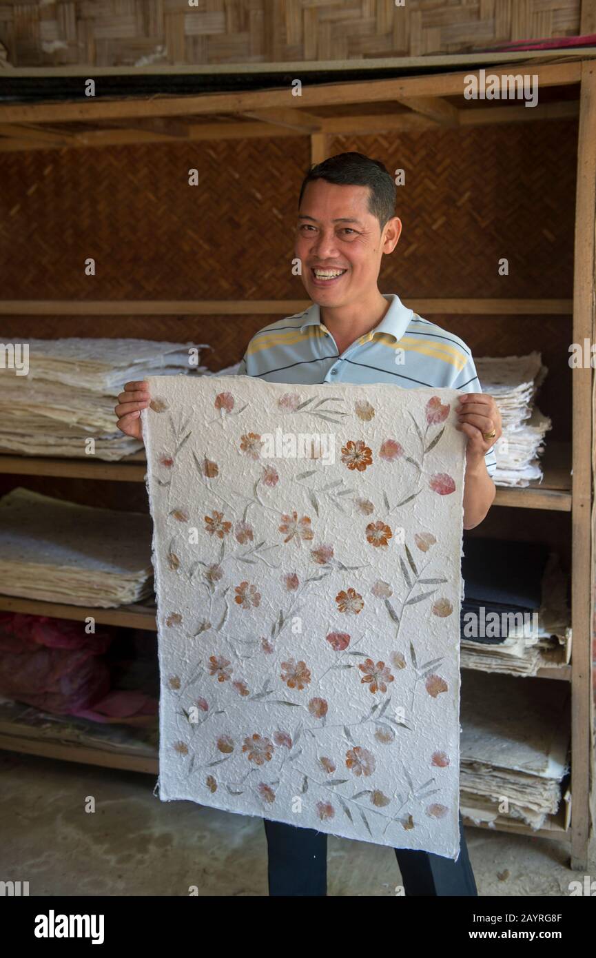 La nostra guida sta mostrando carta di iuta con permesso di bambù e decorazioni floreali in Ban Xang Khong, un villaggio vicino a Luang Prabang nel Laos centrale, che è kno Foto Stock
