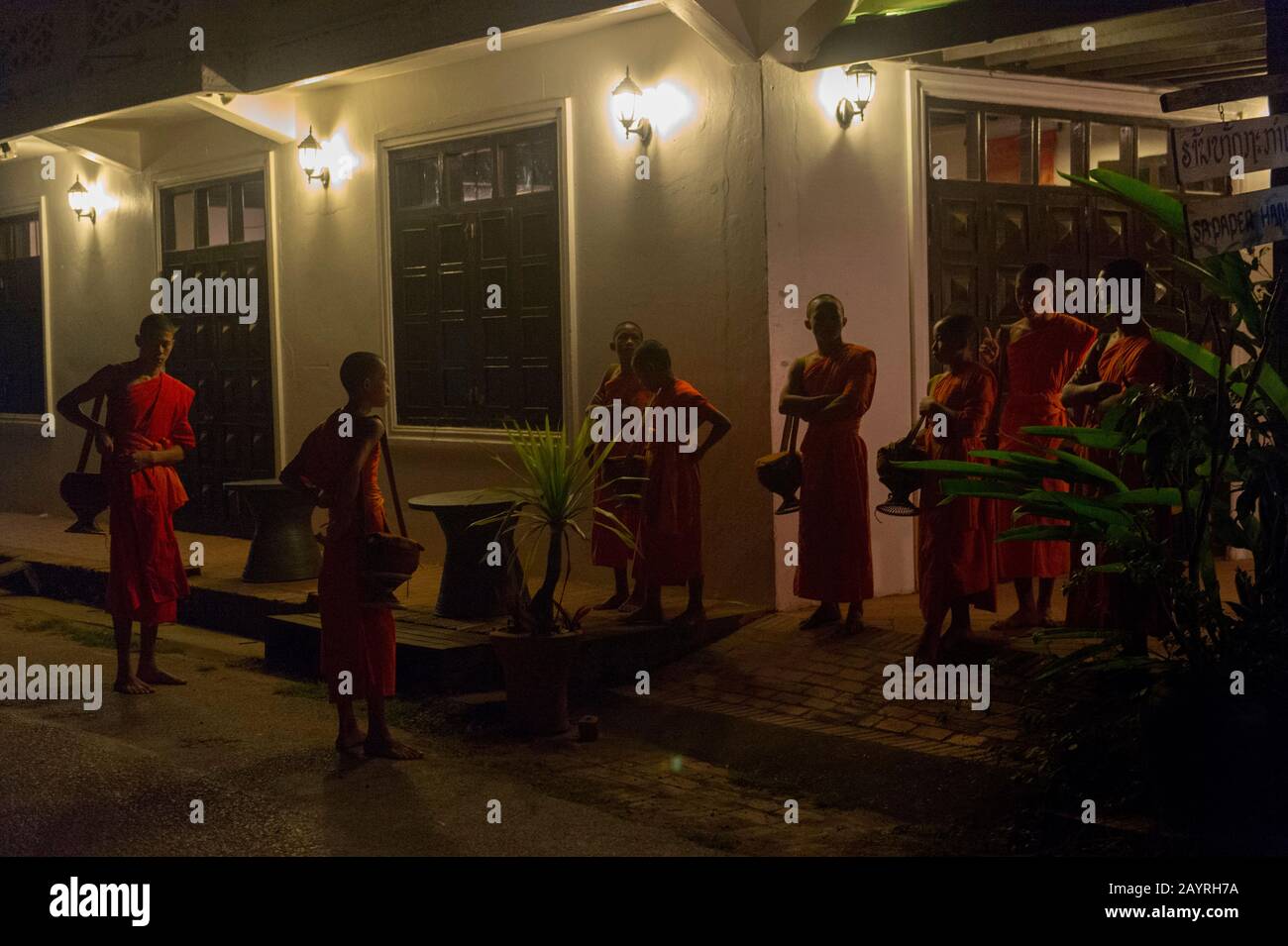 I monaci buddisti si radunano per ricevere elemosine al mattino presto prima dell'alba dal popolo della città patrimonio dell'umanità dell'UNESCO di Luang Prabang Nel Cen Foto Stock