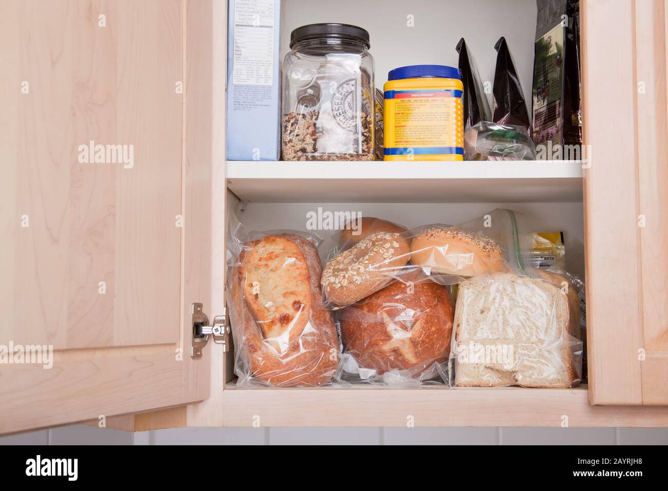 Varietà di pane conservato in sacchetti di plastica in armadio in cucina Foto Stock