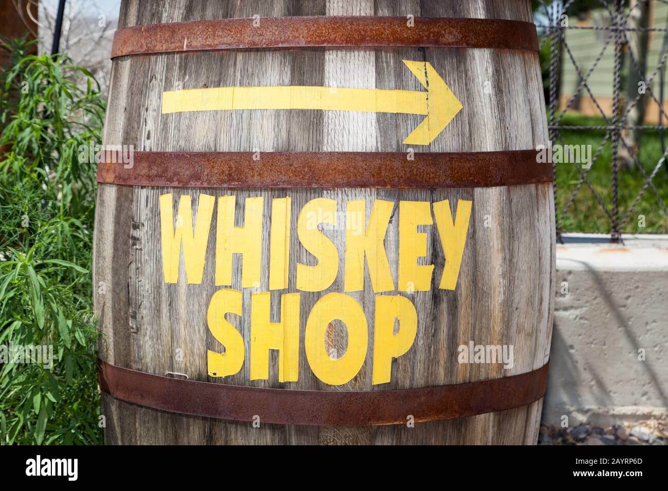 Un vecchio barile di whisky con bande arrugginite è dipinto con le parole whiskey shop e una freccia che punta la direzione. Foto Stock