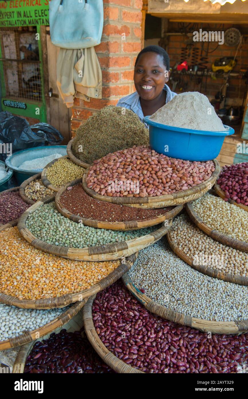 Una donna che vende arachidi, riso, fagioli e altri legumi sul mercato nella piccola città di Zomba in Malawi. Foto Stock