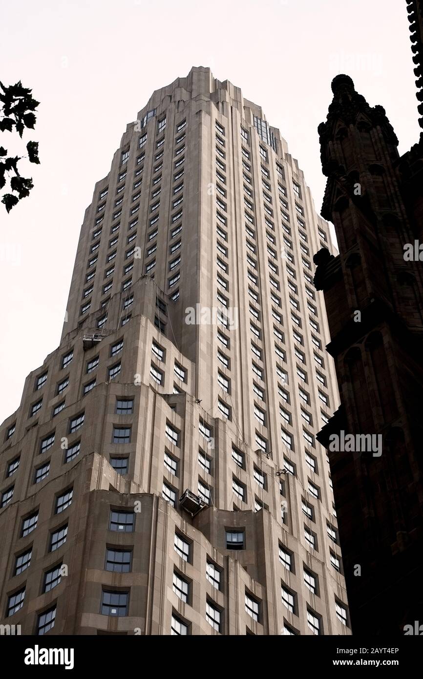 One Wall Street, New York City, una facciata in pietra calcarea fiancheggiata da una finestra Art Deco, un monumentale grattacielo visto contro un dettaglio gotico della Trinità Church Foto Stock